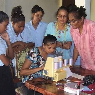 Nanaimo Sewing School Students, under the watchful eyes of Mrs. Habbibullah, right, using the "serger" sewing machine for the first time. 
